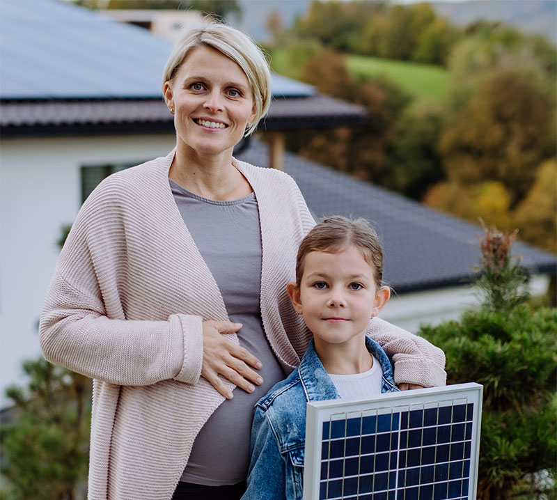 Pregnant woman with daughter holding a solar panel